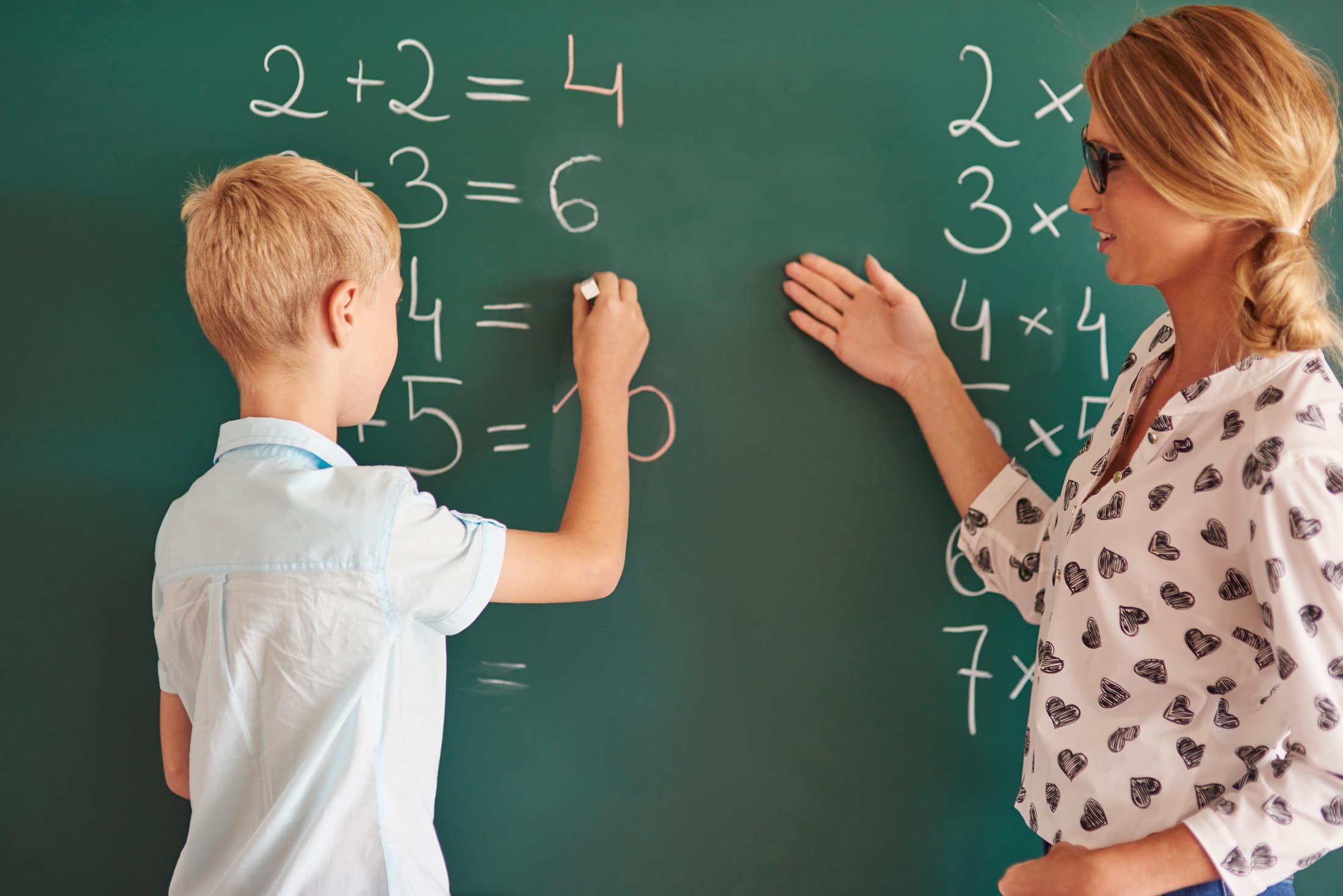 Student standing by a chalkboard with chalk